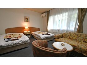 【洋室ツインルーム】ツインベッドを備えたゆったり洋室。ソファーセットでお寛ぎください。