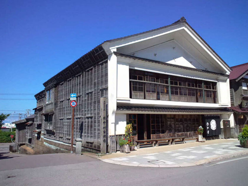 なだらかな斜面に4棟の建物が連なっている家屋。笏谷石（しゃくだにいし）を積み上げた土台に、総ヒバ切妻造りの二階建て母屋から浜側に向け、文庫倉、下ノ倉、ハネダシを通り庭で結ぶ様式で、当時の問屋建築の代表的な造りを見ることができます