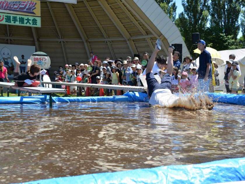 メインアトラクション「泥ブリッジ選手権」。農産物選果用のローラーコンベアーの上を板に乗り滑り、泥のプールにどこまで近づけるか？！